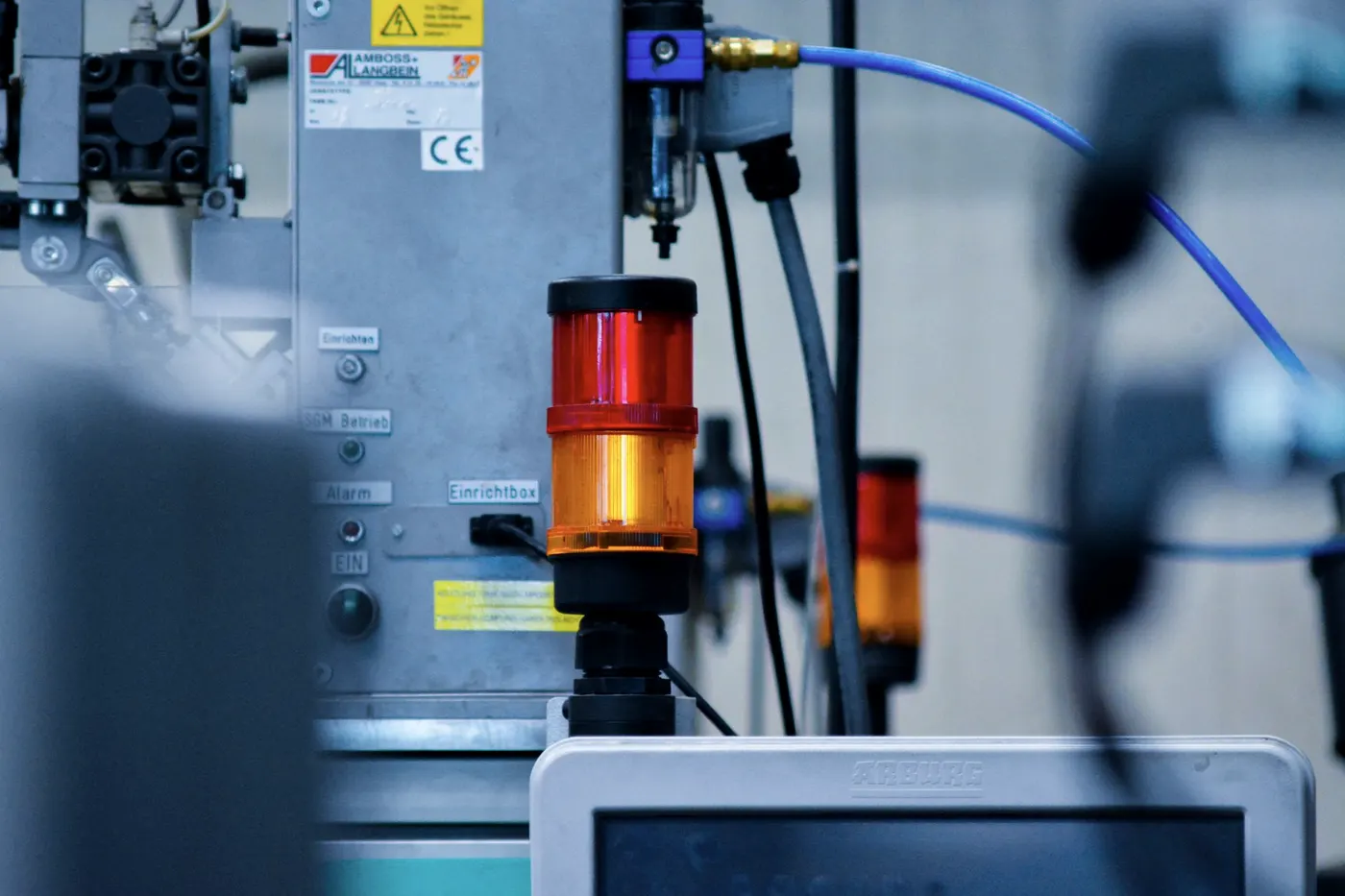Un équipement de production vu de près : sa colonne lumineuse, son écran de commande et les raccords pneumatiques qui l’alimentent.